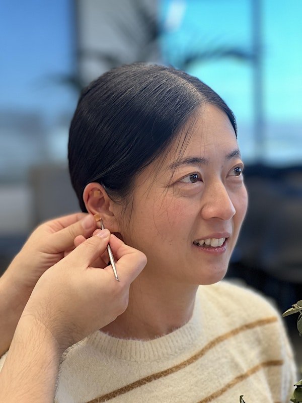 Activating ear seed acupressure point with finger